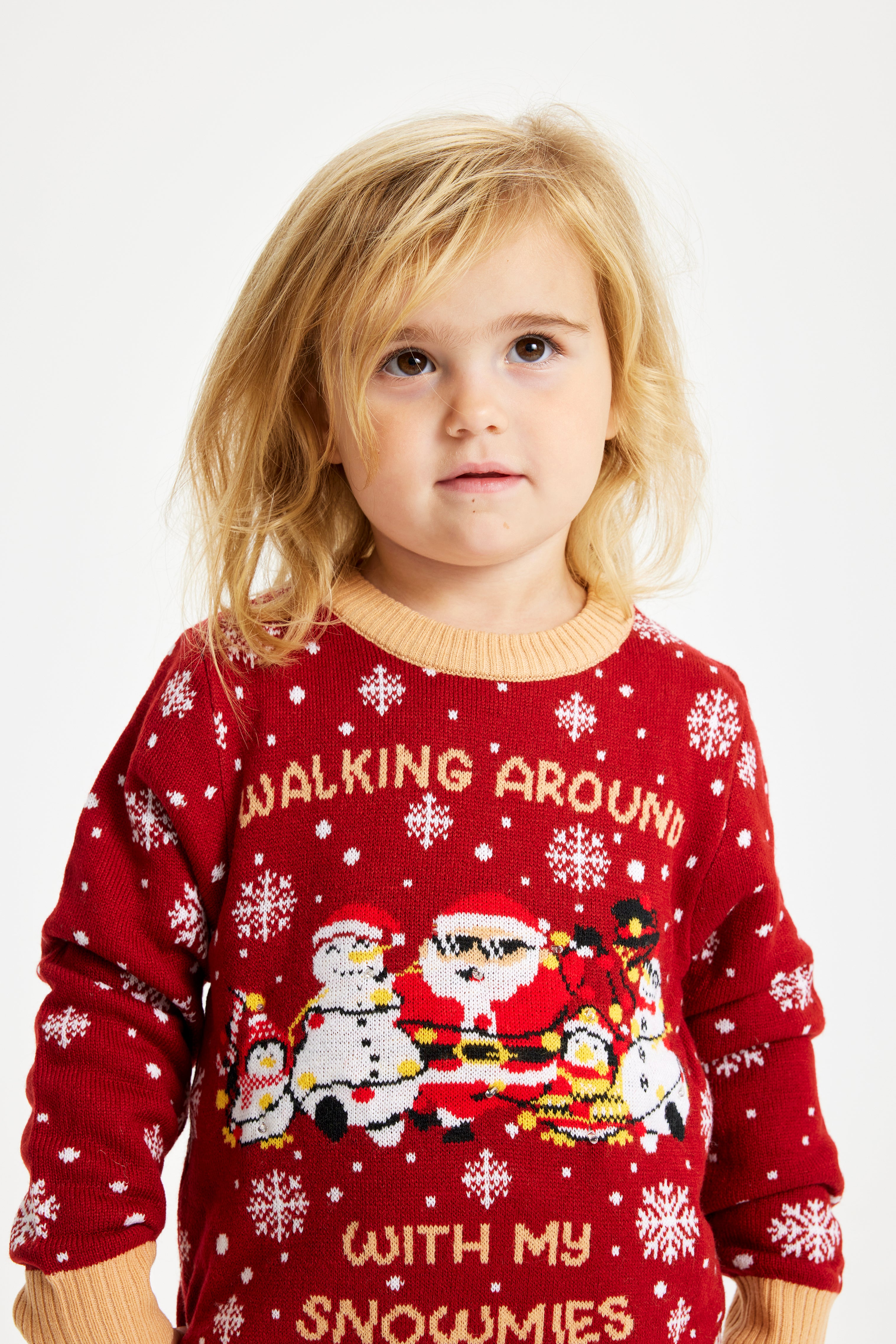 Et barn kigger op og er iført en rød julesweater.